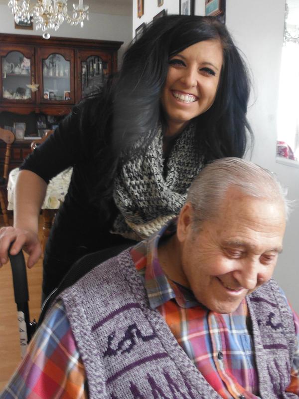 A happy care giver assisting an older man in a wheelchair, who is also happy